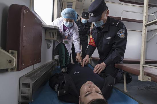 医生向乘警讲解在列车狭小空间如何准确找到心肺复苏的位置。