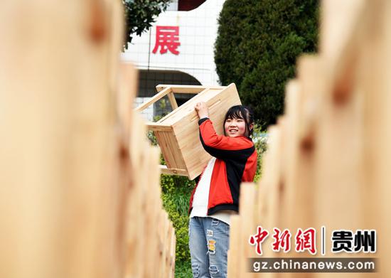 2012年3月15日，贵州省毕节市黔西县铁石小学的一名女同学正兴高采烈地搬运新课桌 熊军万 摄
