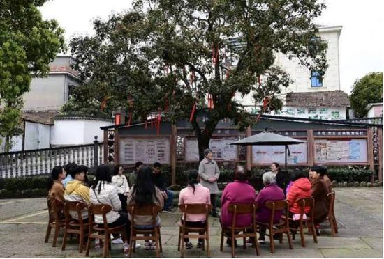 桂花村村民在百年桂花树下，听施丽仙朗诵诗歌。 龚灿供图