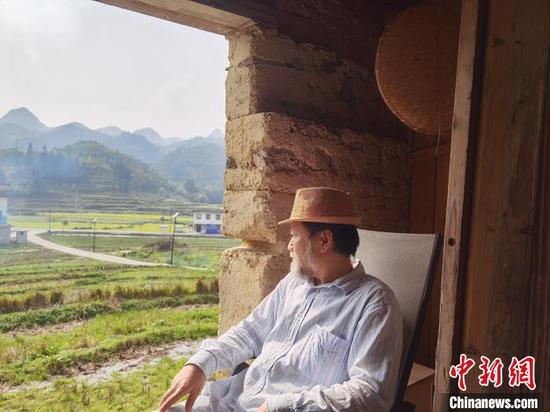 艺术家嵩田坐在“认养”的老屋看外面的风景。　周燕玲 摄
