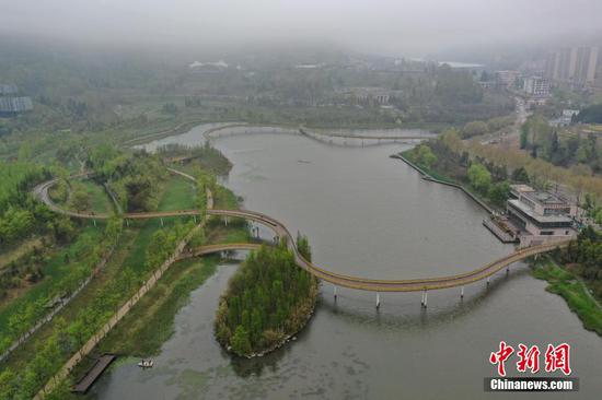 3月25日，贵州省六盘水市明湖湿地公园内的栈道修建于湖面上，从空中鸟瞰宛如一条“飘带”。(无人机拍摄)中新社记者 瞿宏伦 摄