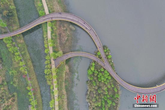 3月25日，贵州省六盘水市明湖湿地公园内的栈道修建于湖面上，从空中鸟瞰宛如一条“飘带”。(无人机拍摄) 中新社记者 瞿宏伦 摄