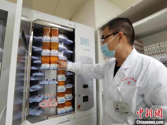 图为在住院部药房工作8年时间的主管药剂师杨天才向记者展示全自动片剂摆药机。　张婧 摄