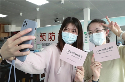 在大王庄街社区卫生服务中心，刚刚接种完疫苗的两位市民，迫不及待拍照合影留念。 彭娜 刘泽瑞 摄影报道