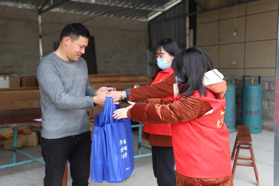 工作人员为壮族种植户送上洗手液、消毒液、口罩等防疫物资。陈永 摄