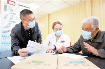 图为刘勇（左一）和汇福养老院护理部部长杨金英（左二）给艾福华老人讲解如何申请长护险。 记者 张立 摄