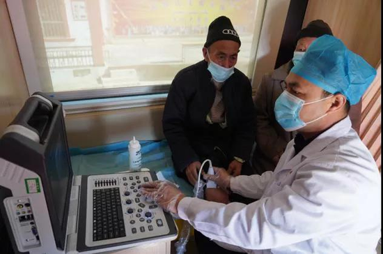 地区肺科医院医生在健康体检车上为72岁的吐尔地·依明老人检查膝关节。