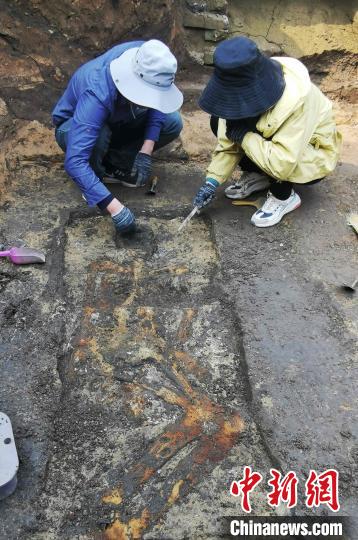 考古人员正在现场用手铲、刷子发掘清理人骨等遗物。　赵晓 摄