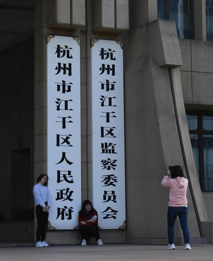 工作人员在杭州市江干区人民政府大楼牌匾下拍照。王刚 摄