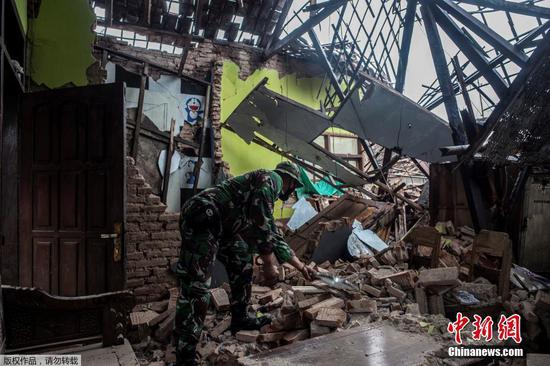 当地时间4月11日，印尼东爪哇南部海域发生6.1级地震后，一名印尼士兵在检查受损的房屋。
