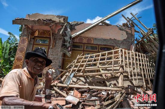 当地时间4月11日，印尼东爪哇南部海域发生6.1级地震后，市民骑车经过受损房屋。