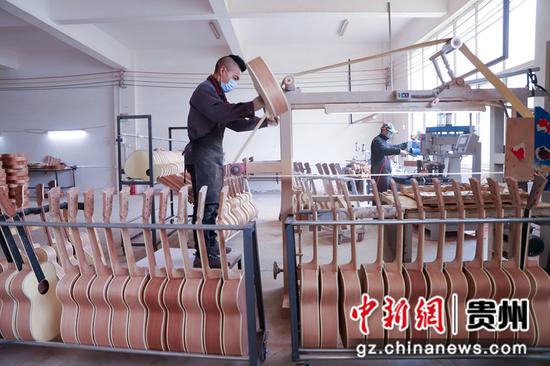 2021年4月11日，在贵州省黔西县文峰街道岔白工业园区多马可乐器生产车间里，工人正在生产乐器——吉他。