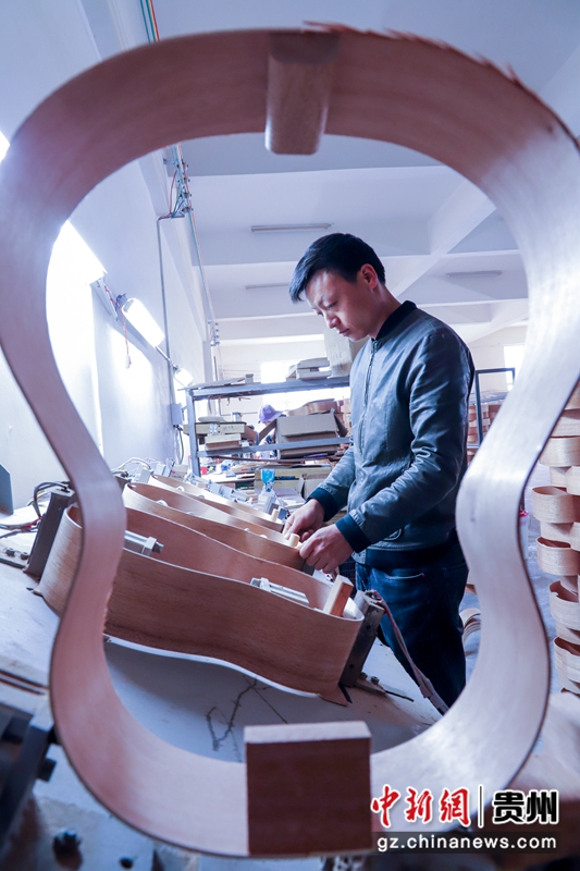 2021年4月11日，在贵州省黔西县文峰街道岔白工业园区多马可乐器生产车间里，工人正在生产乐器——吉他。