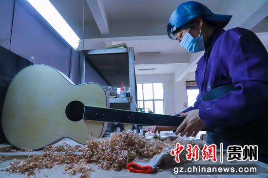 2021年4月11日，在贵州省黔西县文峰街道岔白工业园区多马可乐器厂车间里，工人正在生产乐器吉他。