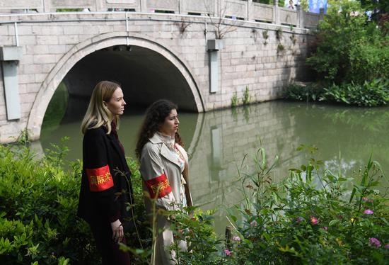 两位国外志愿者在河道边查看河道环境。 王刚供图