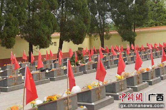 傅金荣在烈士陵园为牺牲的战友擦拭墓碑。易欢 摄