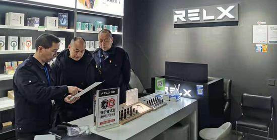 专卖稽查员（左）向电子烟经营者进行法律法规宣传  杨斌 摄