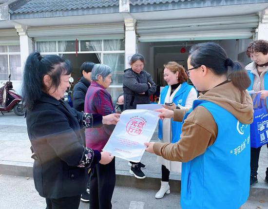 志愿者向村民发放海报。许旭 摄