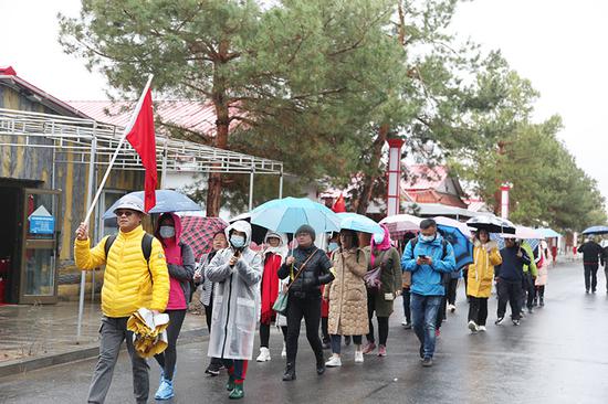 来自北京的游客挥动国旗、高唱国歌在祖国西北边关感受军垦戍边文化。