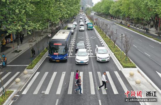 公交车和私家车停车礼让行人（无人机照片）。  王刚 摄