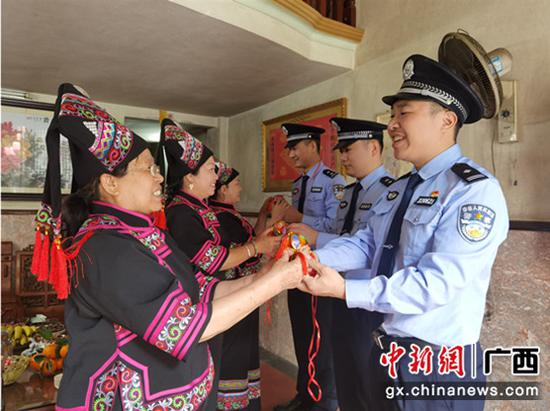 图为“壮族兵妈妈服务队”向民警送上亲手制作的壮乡绣球。林森 摄 崇左:党史教育进壮家 警地共学叙党恩