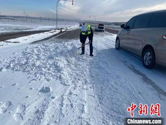 吉木乃县交警铲雪，缓解降雪带来的道路湿滑问题。　乌兰·阿力 摄