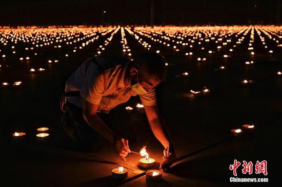 当地时间4月22日，泰国巴吞他尼府，志愿者和僧侣一起点燃33万根蜡烛打造坐佛图像，创造世界最大火焰图像吉尼斯世界纪录。