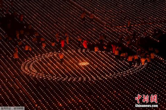当地时间4月22日，泰国巴吞他尼府，志愿者和僧侣一起点燃33万根蜡烛打造坐佛图像，创造世界最大火焰图像吉尼斯世界纪录。