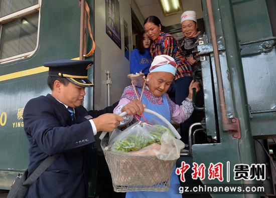 图为列车员帮助民众提菜下车。贵阳客运段供图