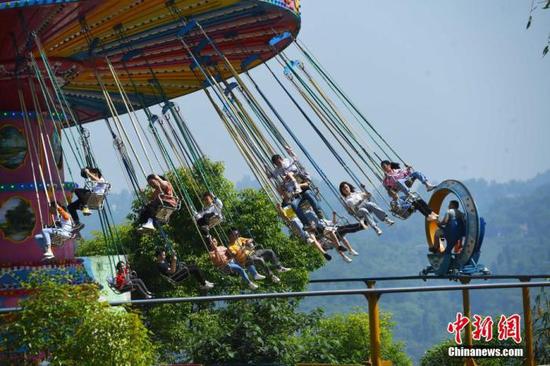 　　5月1日，“五一”节假的第一天， 重庆涪陵红酒小镇景区内的游客乘坐体验游乐设施。　中新社记者 陈超 摄