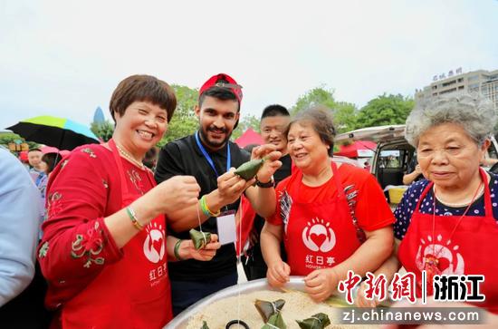 “红日亭”志愿者与外国友人一起包粽子。孙兰香供图