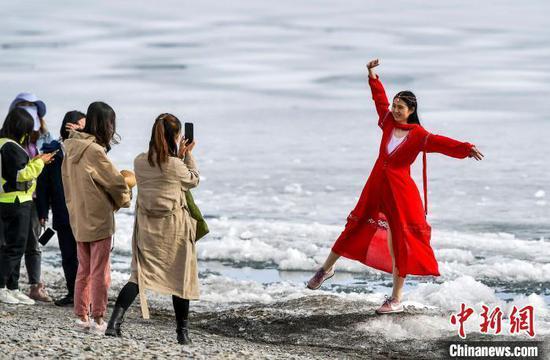 五一假期，紧邻连霍高速公路的新疆赛里木湖，尚未消融的冰雪随风在湖中飘荡，众多游客在湖畔拍照留影。　刘新　摄