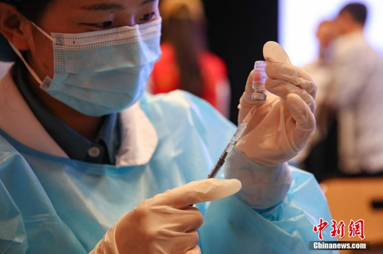 医护人员在贵州民族大学新冠疫苗接种现场用针管抽取新冠疫苗药液。 瞿宏伦 摄