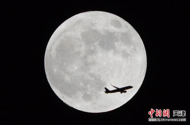 5月26日晚，天津，一架飞机飞过“超级月亮”。当天，全球迎来一次罕见的月全食，此次月全食恰逢年度最大满月，因此被称为“超级月全食”，“超级月亮”和“月全食”同时在夜空中上演。

中新社记者 佟郁 摄
