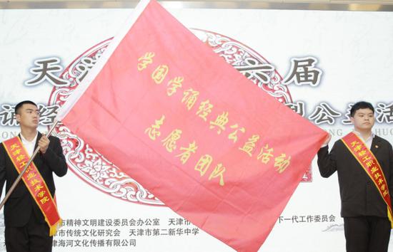 由天津市传统文化研究会秘书长向本次活动志愿者团队代表（轻工技术学院团委）授旗。