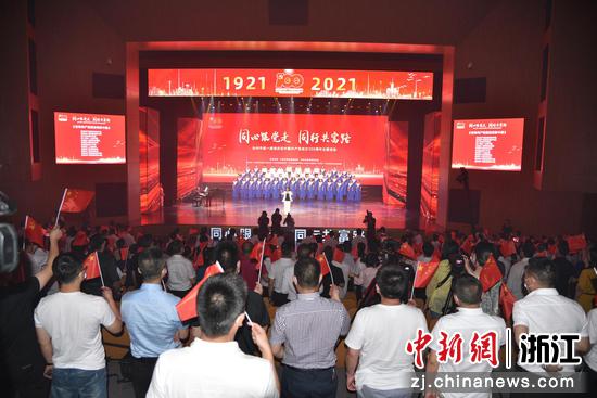 活动现场观众举起红旗共同唱响《没有共产党就没有新中国》 范宇斌 摄