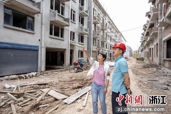缙云县烟草专卖局党员专班成员刘耀法向安置移民了解房屋建设情况。 赵洁如 摄