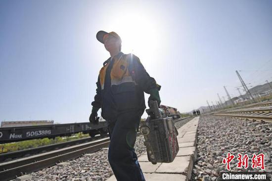 7月6日，兰州北编组站“90后”列车修理师郭皎手提列尾穿梭在铁路股道间。　杨艳敏　摄