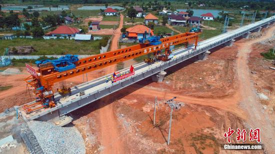 7月5日，随着架梁作业人员操作着JQT-180型架桥机将逢通特大桥最后一片T梁落在桥台上，由中铁五局六公司承建的中老铁路最长桥梁——逢通特大桥架设完成，这标志着“一带一路”标志性工程中老铁路正线架梁贯通。逢通特大桥位于老挝首都万象市，桥长7528.56米，共计227跨桥梁，桥梁运输、架设安全管理难度大，是本标段的控制工程。 中新社发 谢永彬 摄