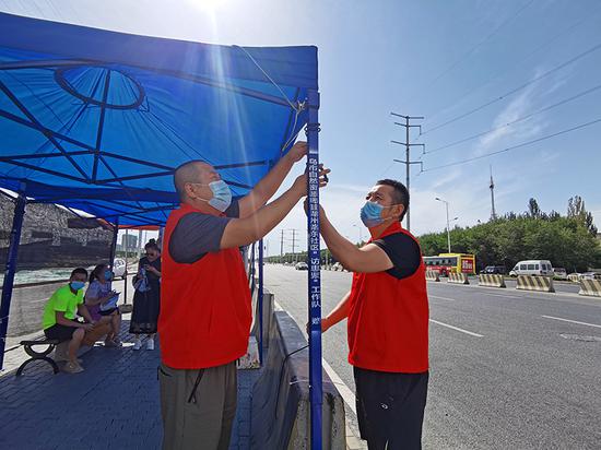 志愿者在烈日下安装遮阳伞。
