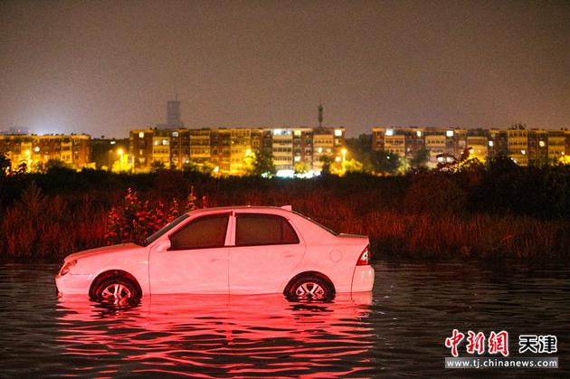 7月13日，天津，暴雨过后，一辆汽车搁浅在积水中。