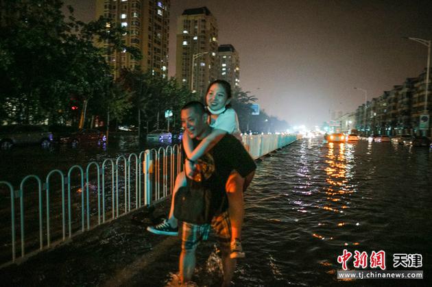 7月13日，天津，暴雨過后，市民走過積水路面。