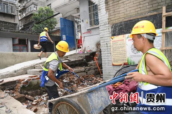 7月15日，在贵阳市南明区兴隆片区老旧小区改造项目建设现场，工人正在电力巷改造现场清理建筑垃圾。