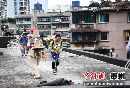 7月15日，在贵阳市南明区兴隆片区老旧小区改造项目建设现场，工人正在电力巷改造现场清理房顶建筑垃圾。