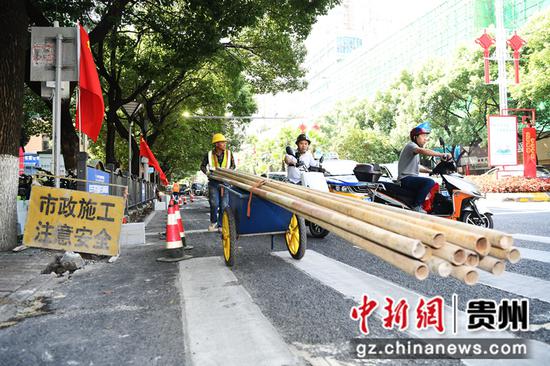 7月14日，在贵阳市南明区兴隆片区老旧小区改造项目建设现场，工人正在搬运钢管进行外架搭设。