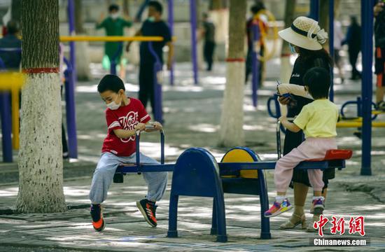 7月15日，新疆乌鲁木齐市体育公园，小朋友在家长的带领下在公共健身器械上玩耍。据介绍，该市正推进城区“15分钟体育健身圈”建设，将在不少于150个小区、公园、小游园等场所新建一批以室外为主的公共体育设施。 中新社记者 刘新 摄