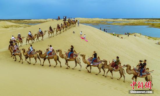 游客骑乘骆驼游览神女湖环线沙漠景色。李飞 摄