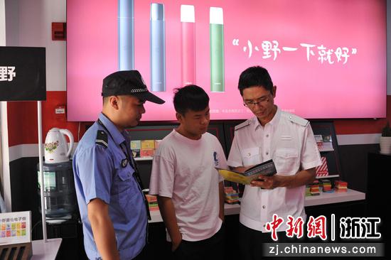　　遂昌县烟草专卖局执法人员（右一）向电子烟销售户宣传《中华人民共和国未成年人保护法》。巫晓俊 摄