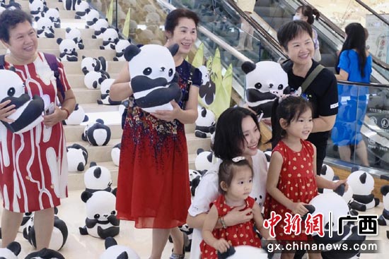图为巡展志愿者帮助摆放环保纸大熊猫宝宝们