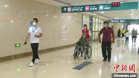 101岁的白内障患者塔吉汗·艾克力在医务人员帮助下前往手术室。　热孜万古 摄